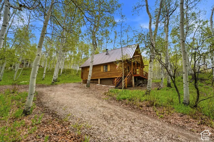 Log cabin exterior with a metal roof and a prominent wooden deck