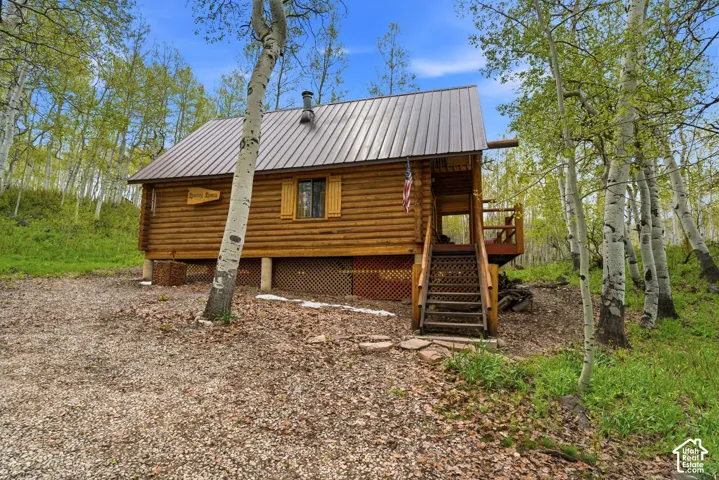 Log cabin exterior featuring a metal roof, wood siding, and an elevated porch with wood stairs