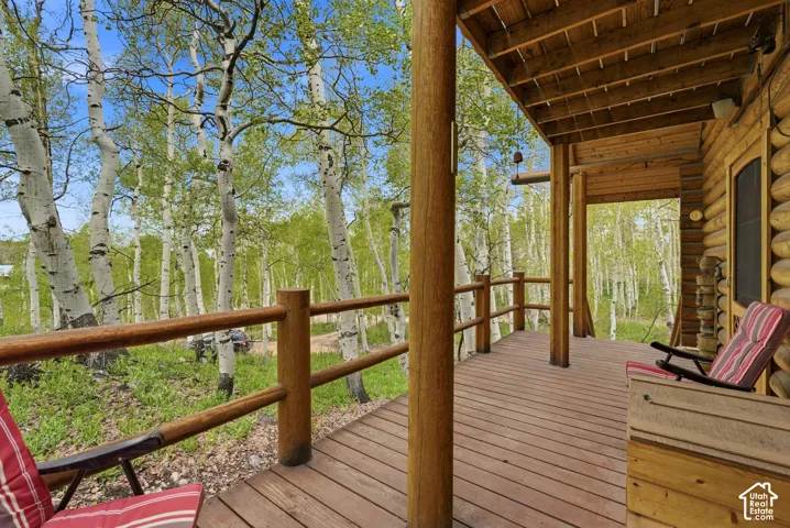 Expansive wooden deck featuring rustic log columns, a matching log railing, and exposed wood ceiling joists