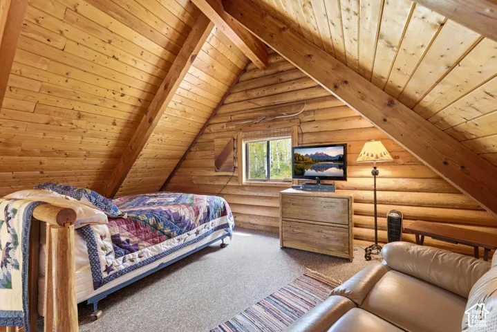 Sloped wood-paneled ceilings with exposed wood beams, horizontal log walls, and a window providing natural light