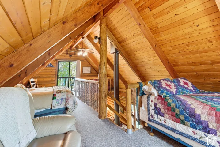 Lofted space featuring exposed wood beams, wood-plank walls, and wood-finish flooring