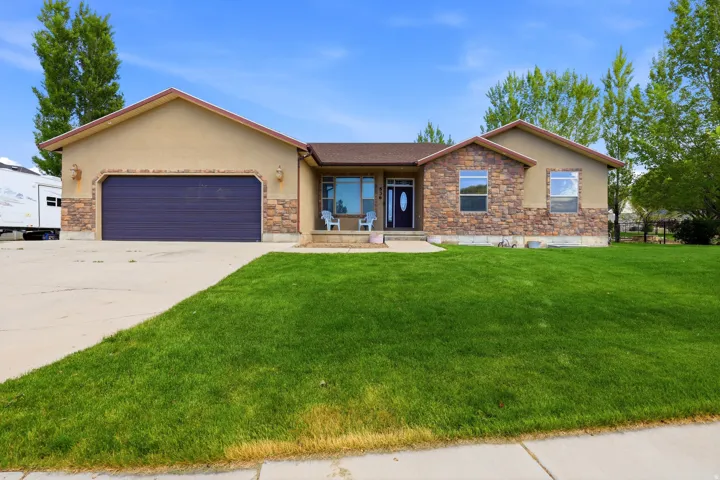 Front exterior featuring a stucco and stone facade, an attached two-car garage, a covered porch entry, and a concrete driveway