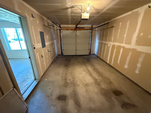 Unit B - Attached single-car garage featuring a roll-up door, exposed ceiling joists, and an overhead garage door opener