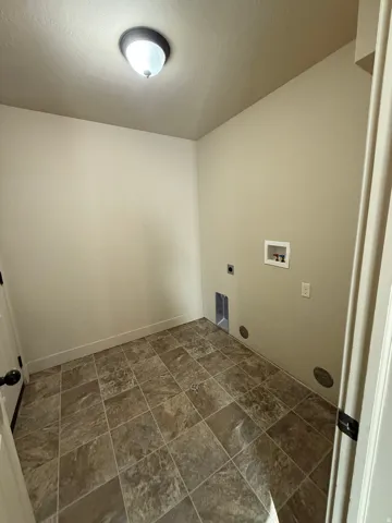 Unit C - Dedicated laundry area featuring durable tile flooring, utility hookups, and a flush-mount ceiling light
