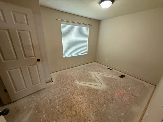 Unit B - Interior room featuring subflooring, a window with blinds, and a paneled door with dark hardware