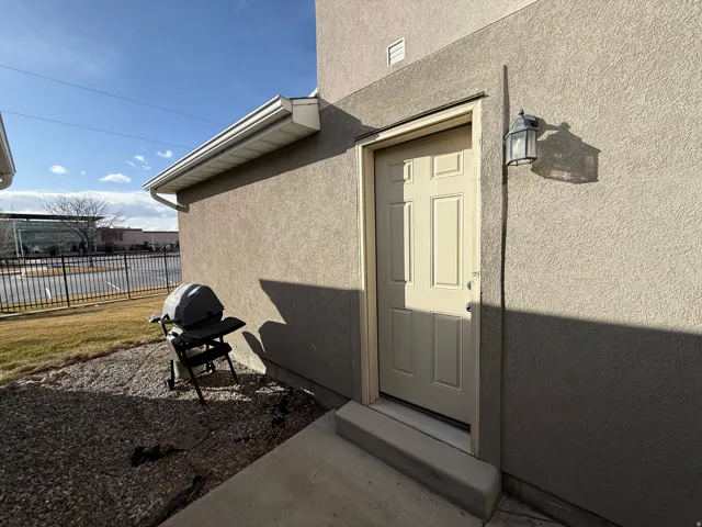 Unit C - Exterior stucco finish with a paneled entry door, concrete step, and wall-mounted lantern light fixture