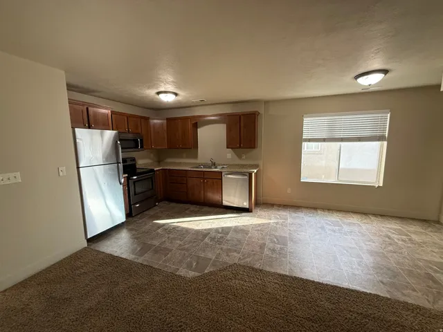 Unit C - Open-concept kitchen and dining area featuring warm wood cabinetry, stainless steel appliances, a tiled floor, and recessed lighting
