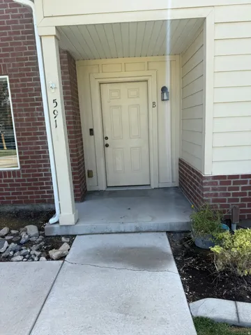 Unit B - Entryway featuring a panel door with transom detailing, brick facade, and a covered porch