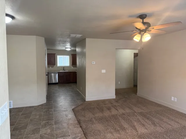 Unit A - Open-concept living area featuring neutral-toned walls and a ceiling fan with integrated lighting