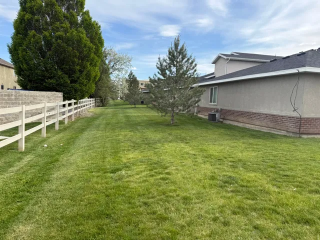 Expansive green lawn with mature trees and a white split-rail fence