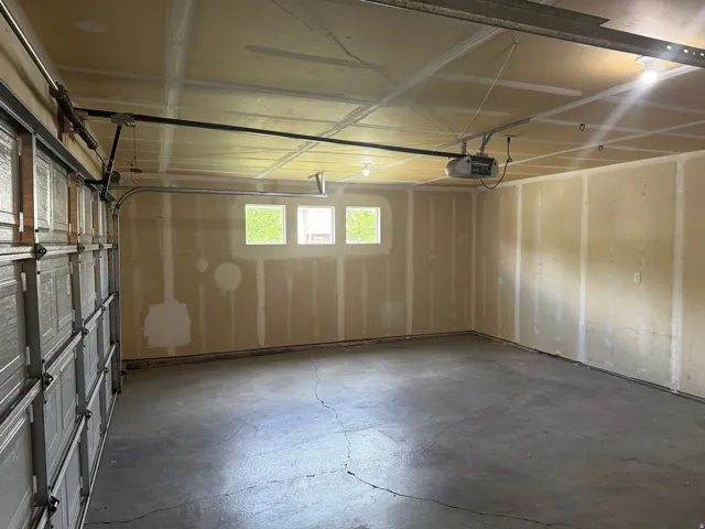 Unit A - Spacious two-car garage featuring a concrete floor, three transom windows, a sectional overhead door, and an automatic garage door opener