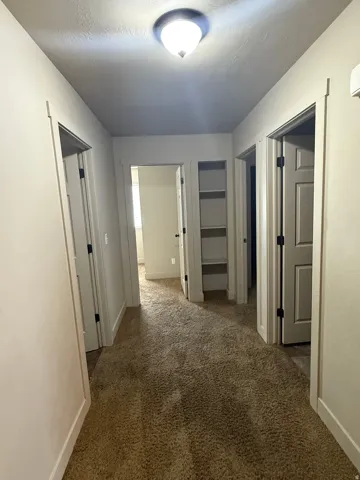 Unit A - Hallway featuring textured carpeting and light-toned walls