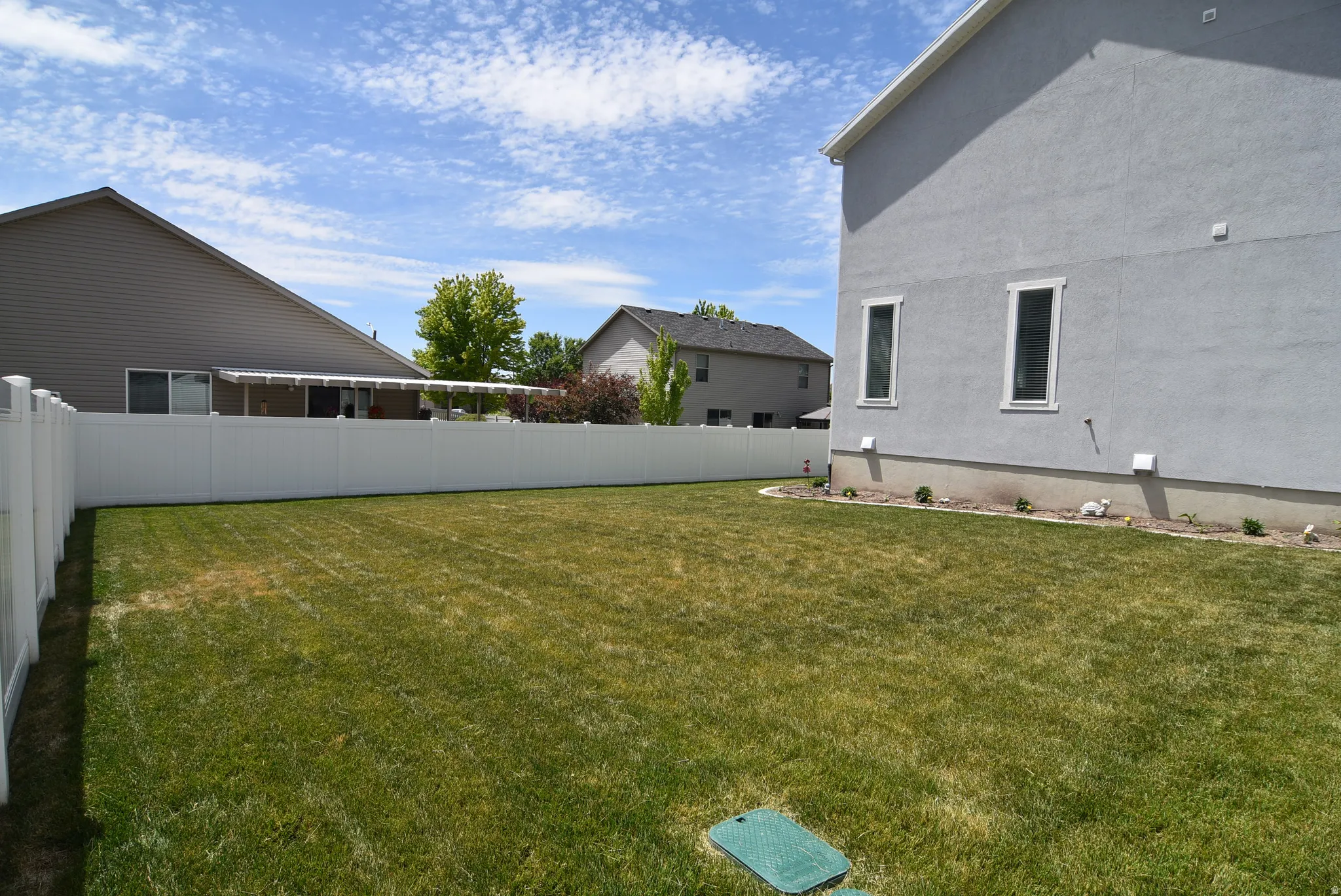 Expansive green lawn framed by a white vinyl privacy fence