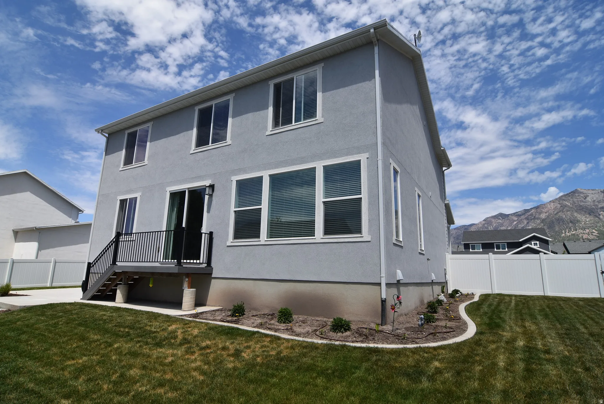Contemporary rear elevation featuring a light gray stucco finish and multiple windows