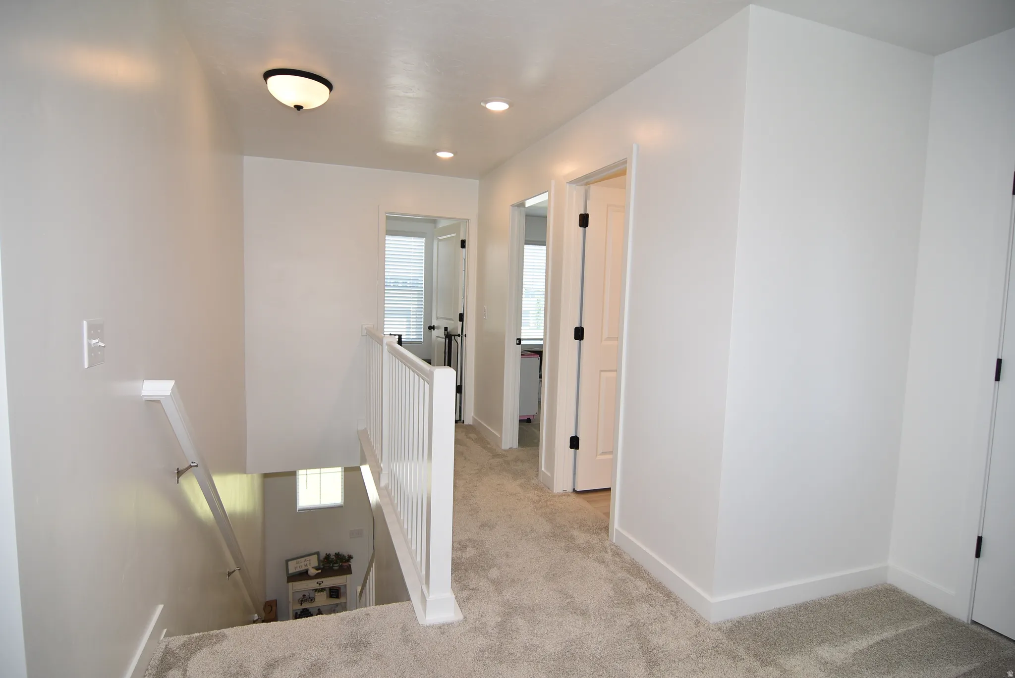 Upper-level landing featuring light gray carpeting, white painted walls, and overhead flush-mount lighting