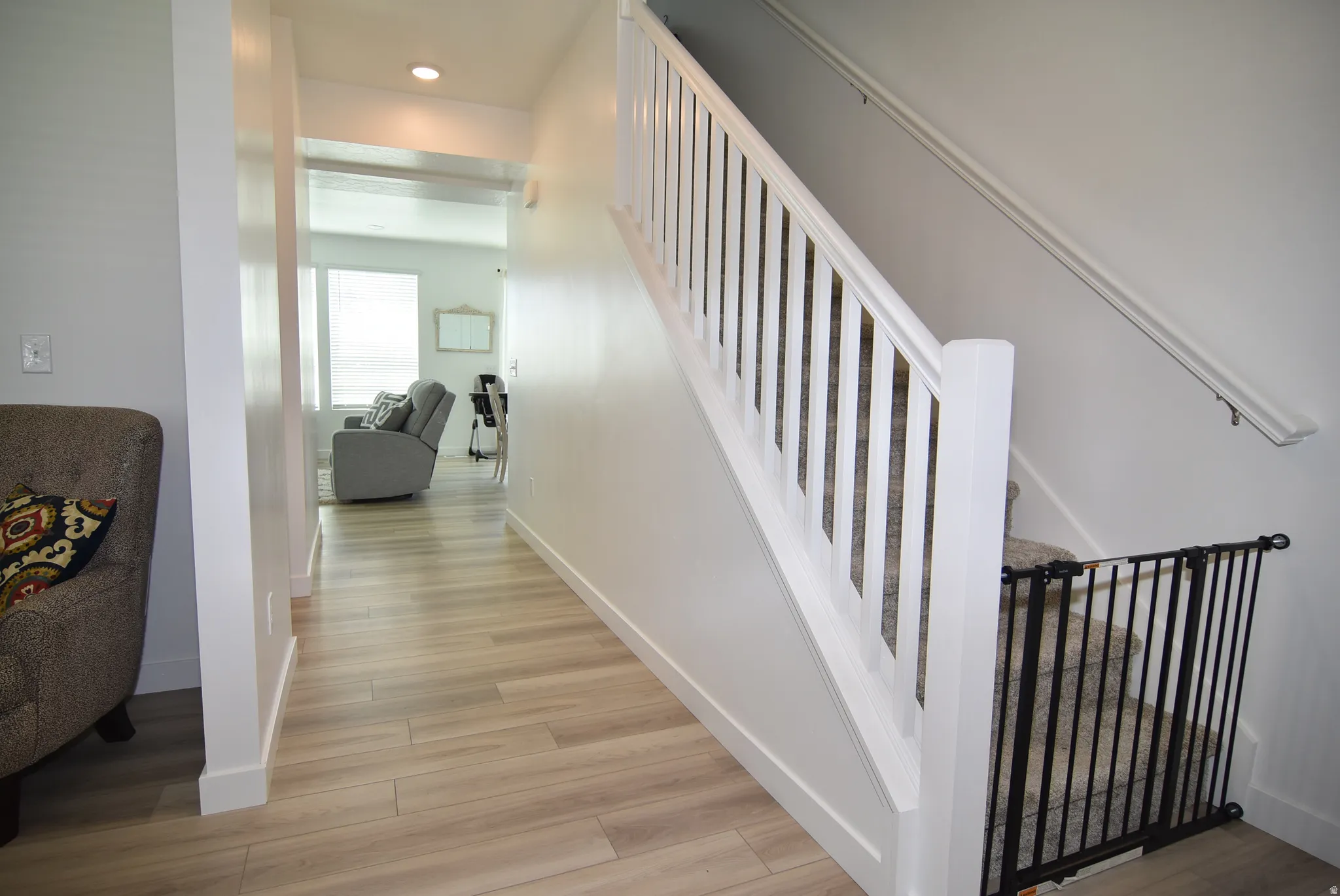 Entryway featuring light wood-finish flooring, white baseboards, and a white staircase with carpeted treads