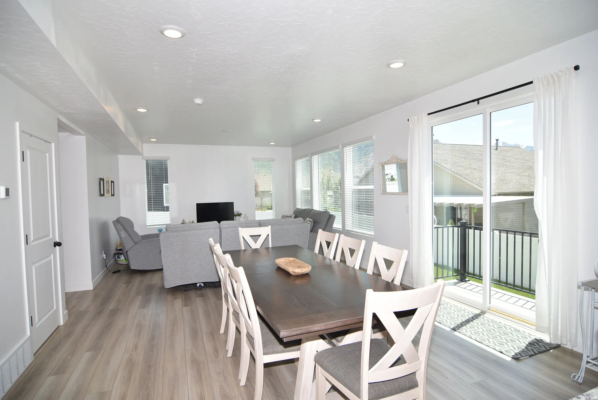 Open-concept living space with wood-finish flooring, recessed lighting, and white walls