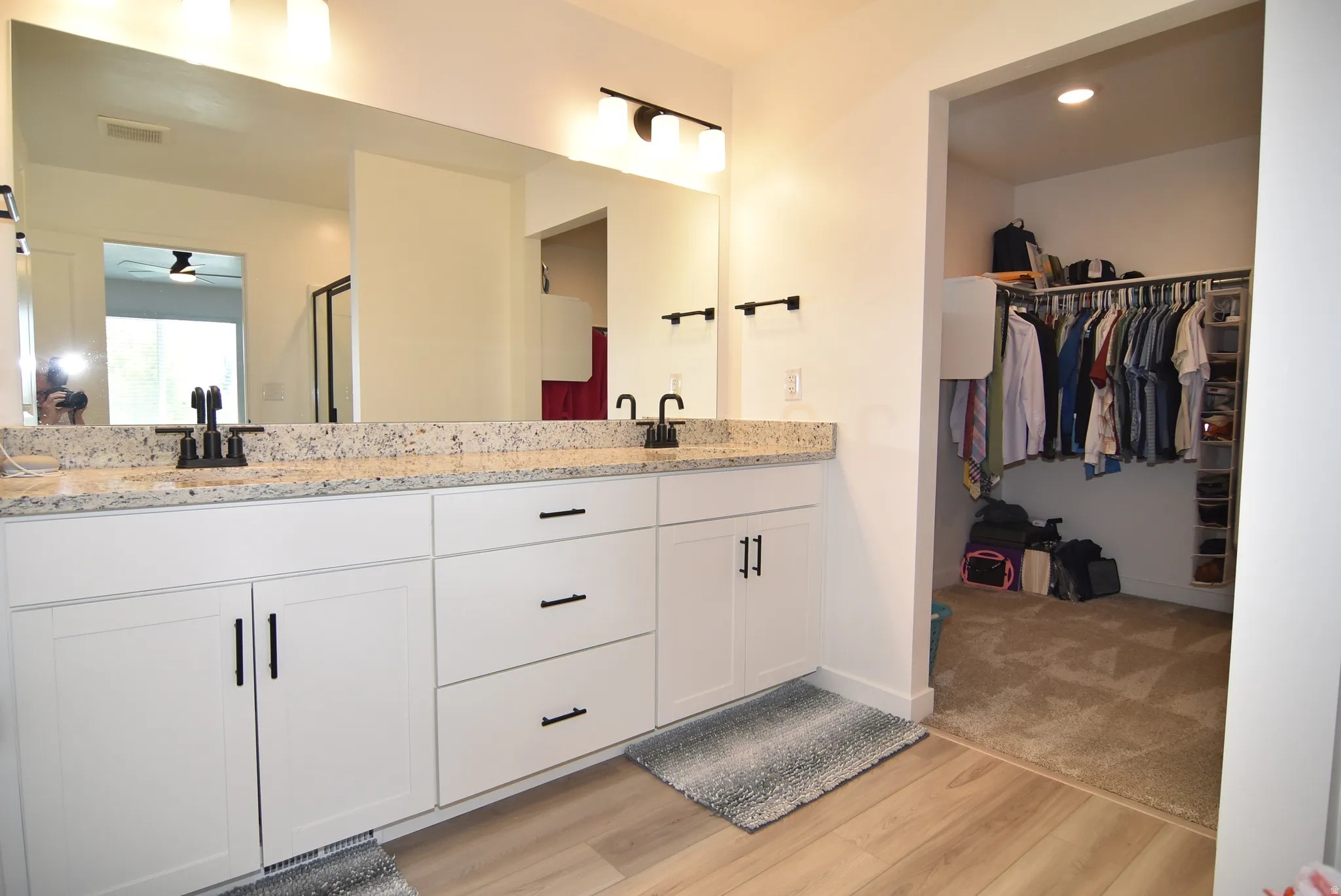 Double vanity featuring a light-toned granite countertop, two undermount sinks, and matte black fixtures