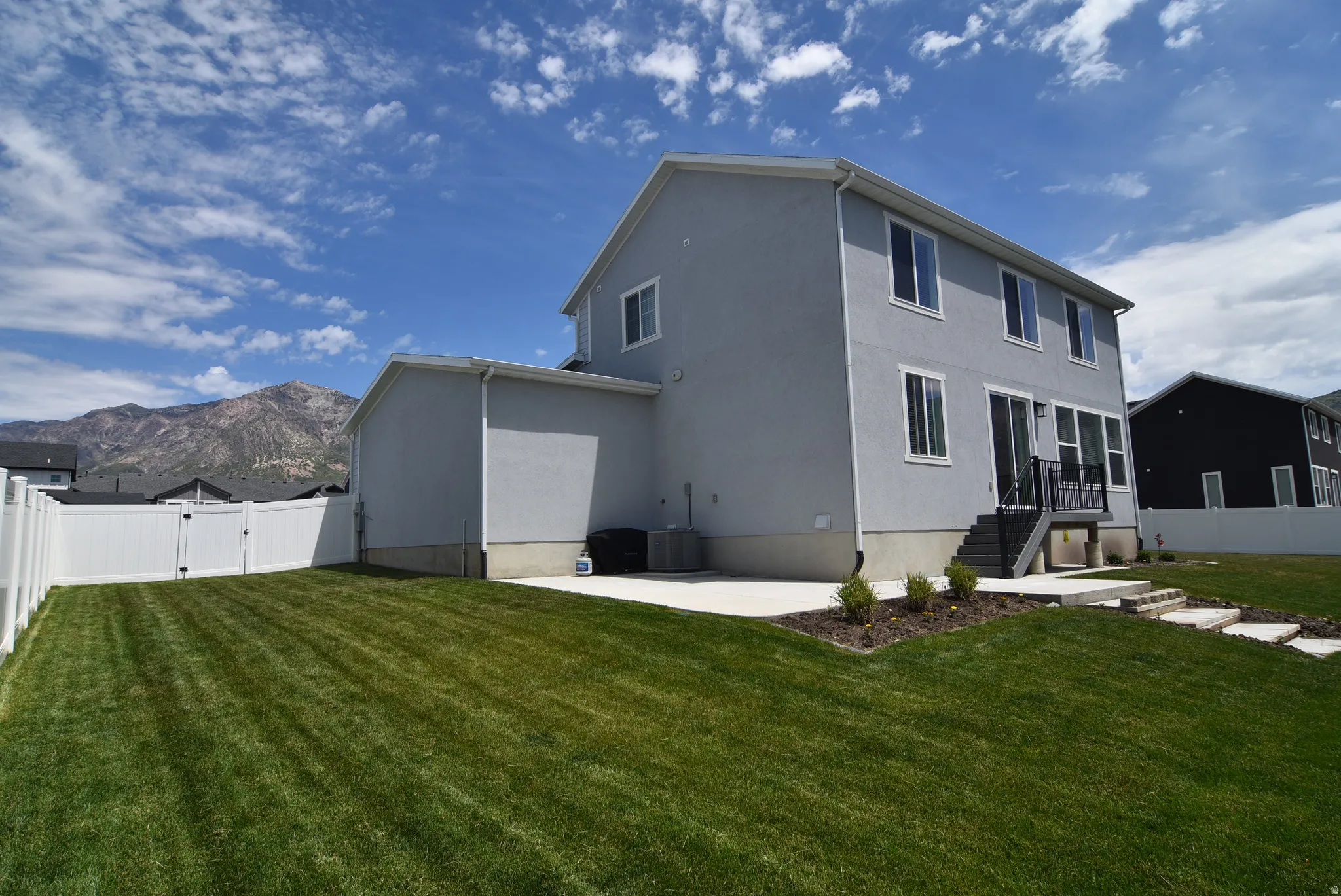 Well-maintained lawn with a white vinyl privacy fence and a concrete patio