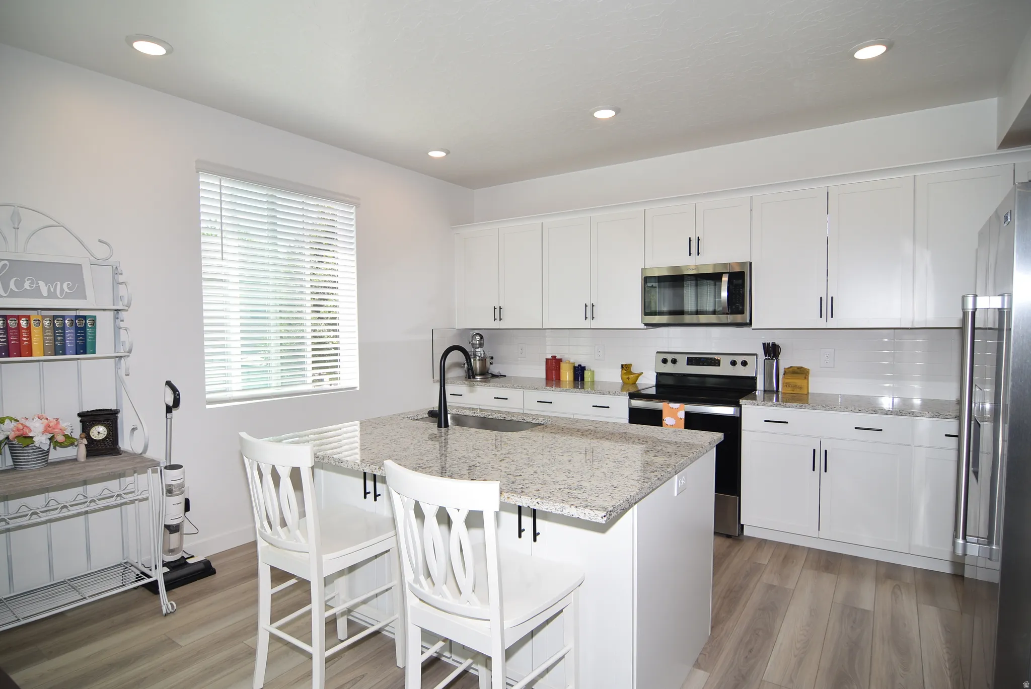Kitchen featuring a central island with counter seating, granite countertops, and white shaker-style cabinetry