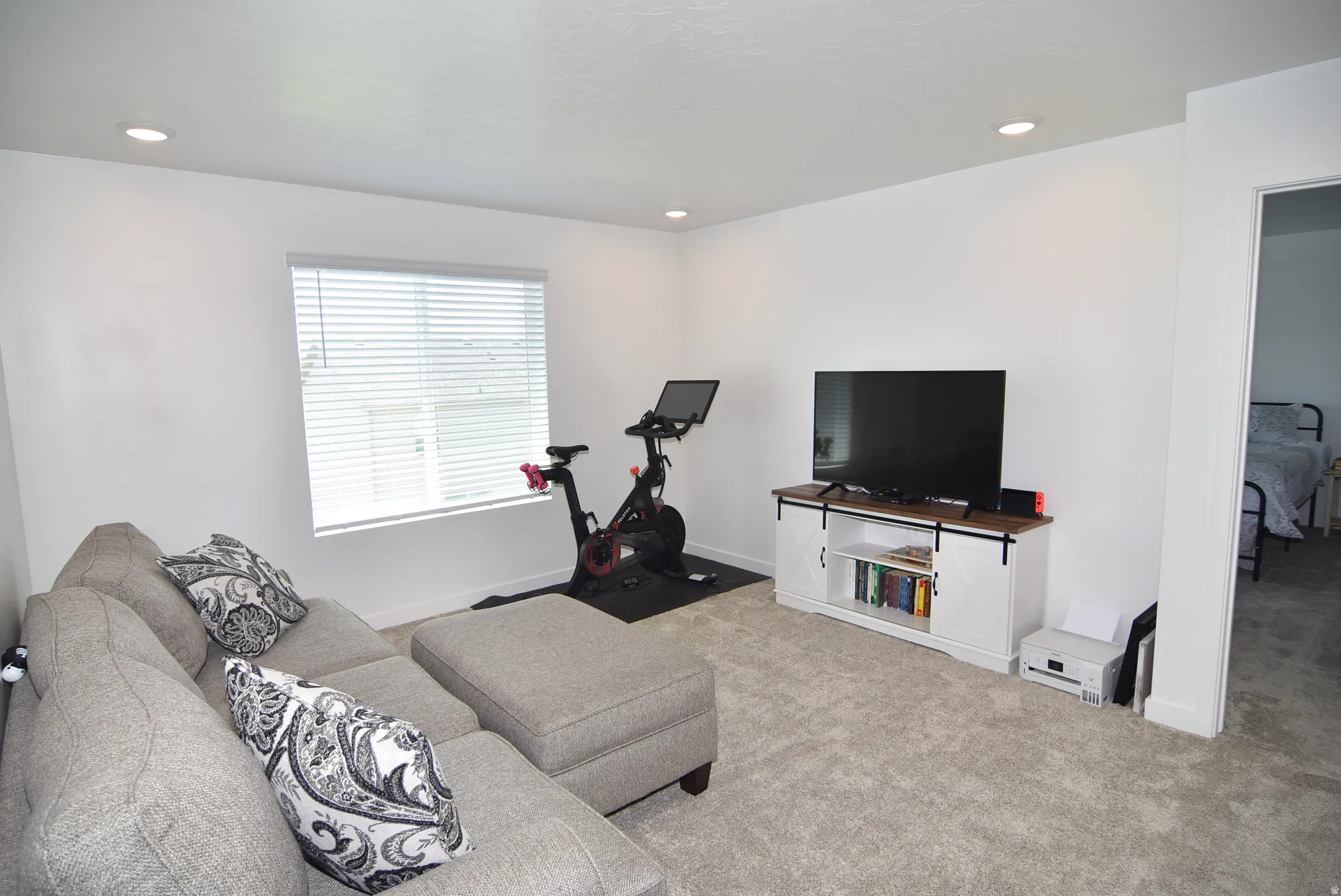Spacious room with plush carpet flooring, recessed lighting, and a window with blinds