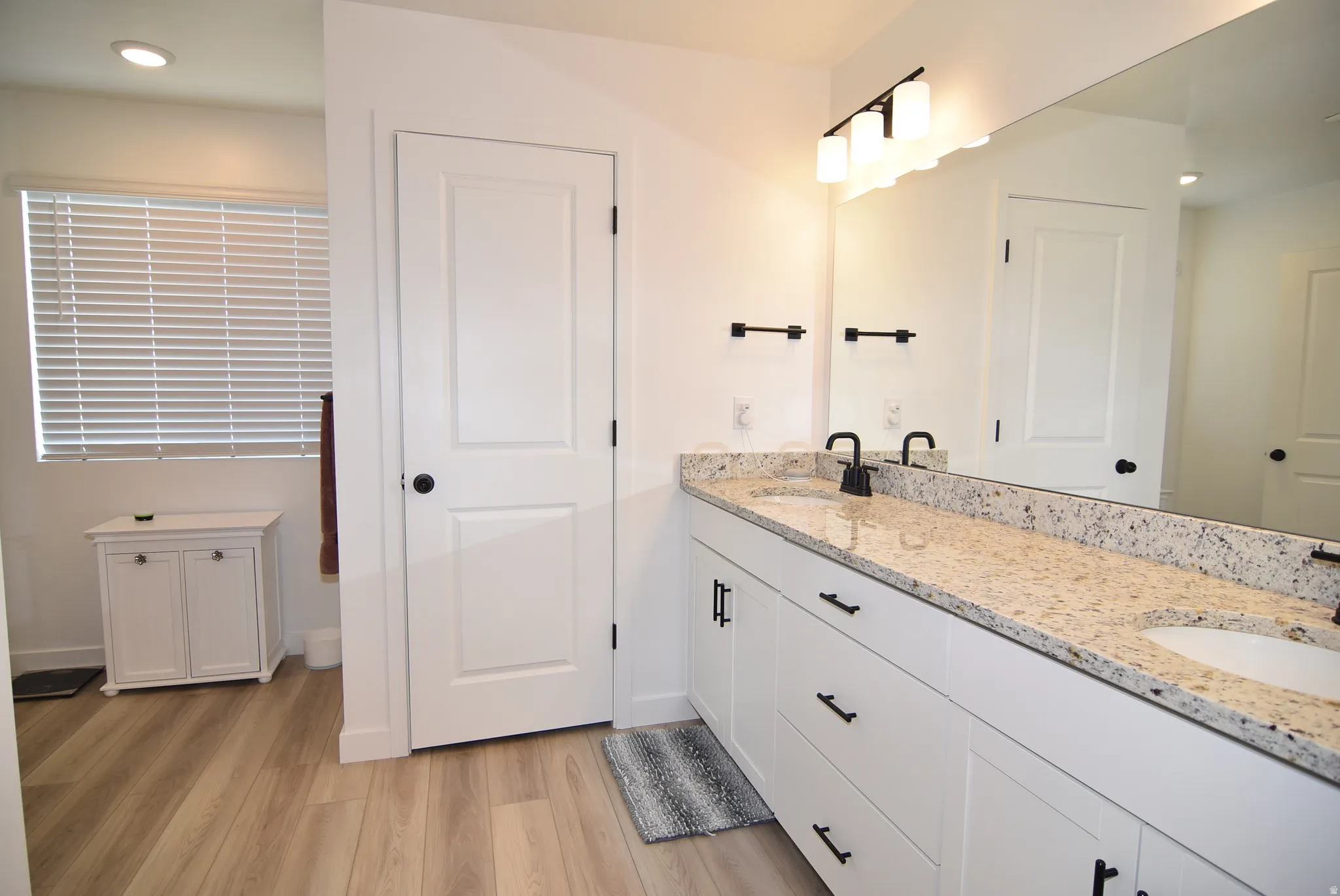 Owner's bathroom with Dual vanity and granite countertop, white cabinetry, undermount sinks, and matte black fixtures