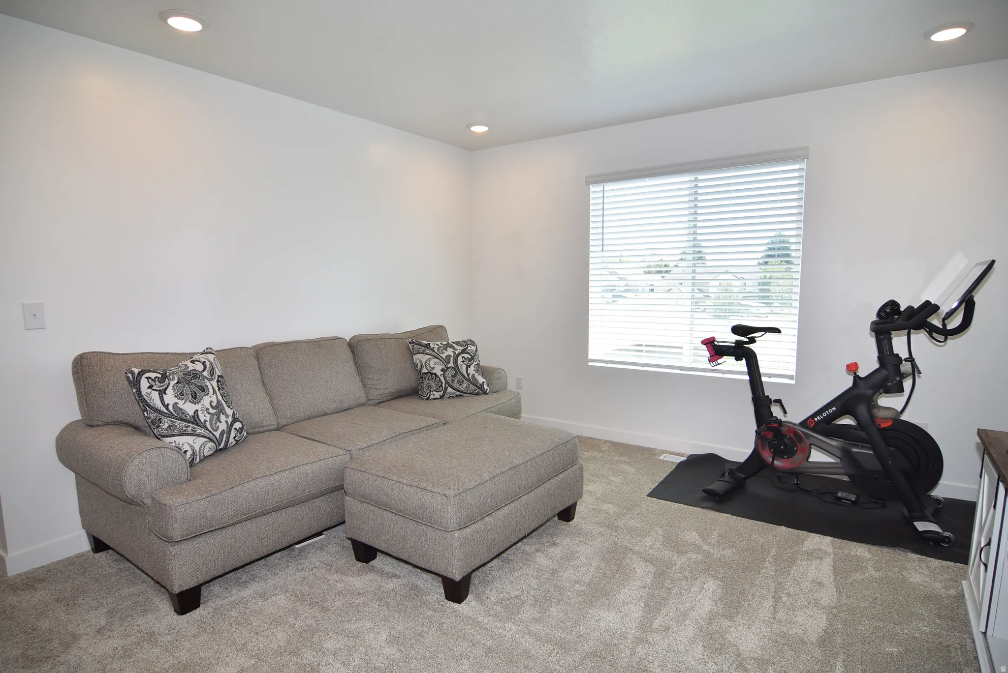 Spacious room featuring light-colored carpeting, recessed lighting, and a window with blinds
