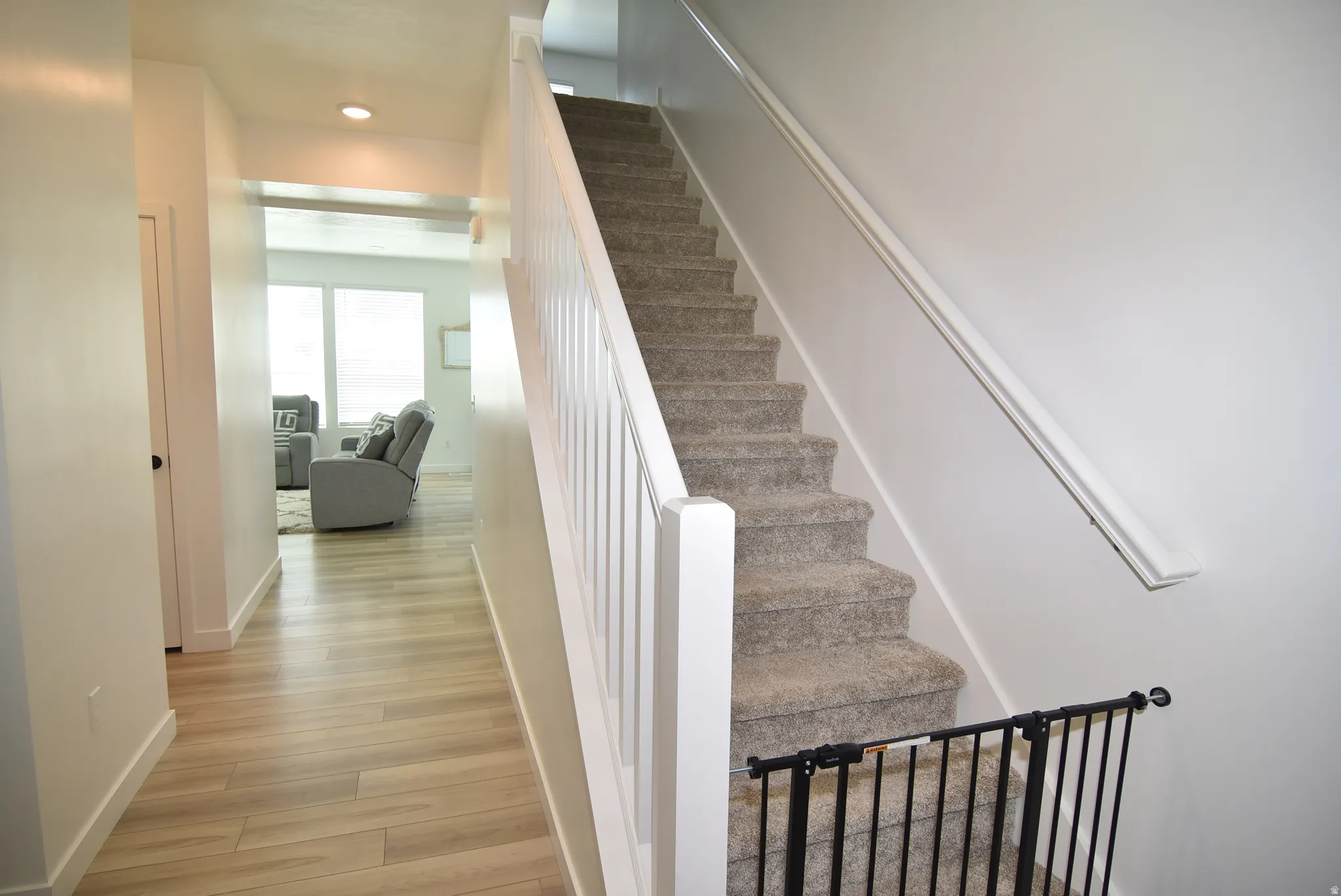 Carpeted staircase with white balusters and handrail