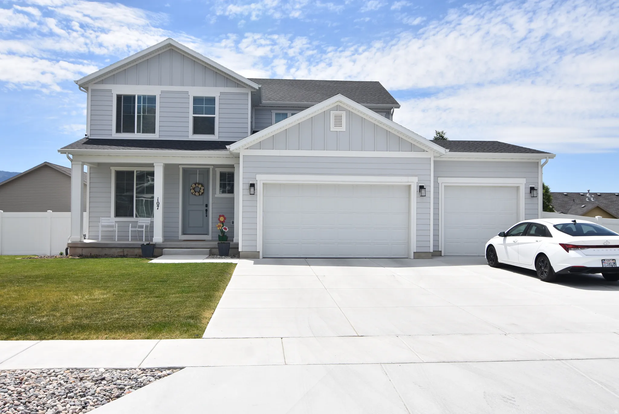Contemporary two-story residence with a light gray siding exterior, featuring a covered porch entry