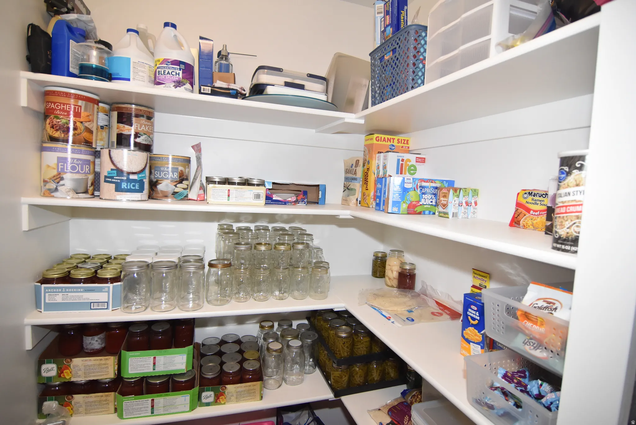 Spacious pantry featuring extensive shelving, white finishes, and a functional corner configuration