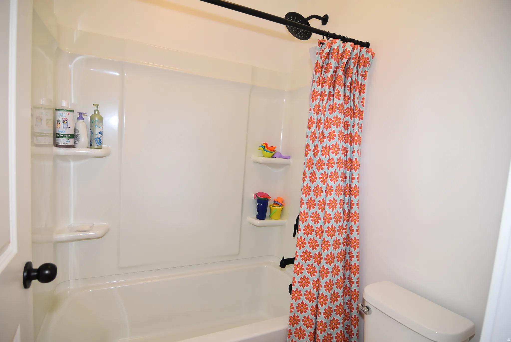 Bathroom #2 White fiberglass tub and shower combination unit featuring integrated shelving and a dark bronze shower fixture