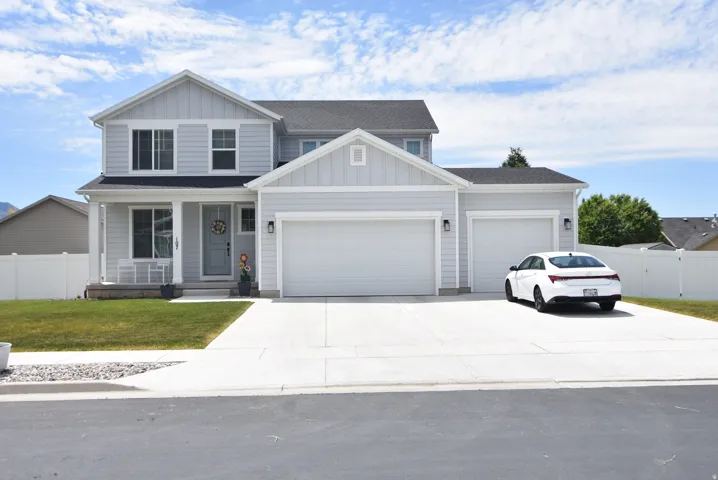 Two-story residence featuring light gray siding with white trim, a covered front porch, and a two-car garage