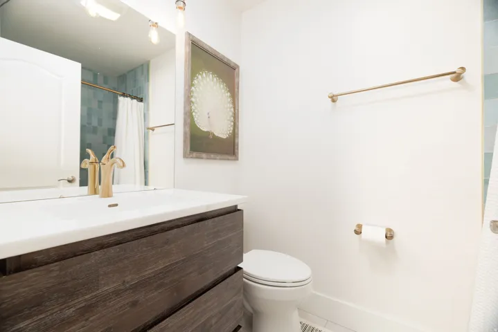 Vanity featuring a white countertop with integrated sink and gold-tone faucet