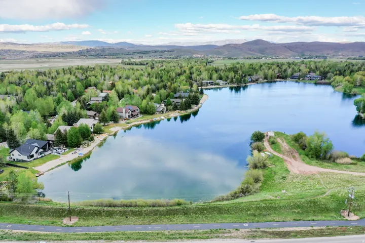 Expansive lakefront setting featuring a private lake, surrounding residential properties, and distant mountain ranges