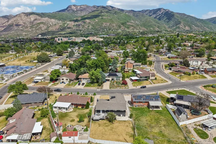 Residential neighborhood featuring a variety of single-family homes, mature trees, and mountainous terrain in the background