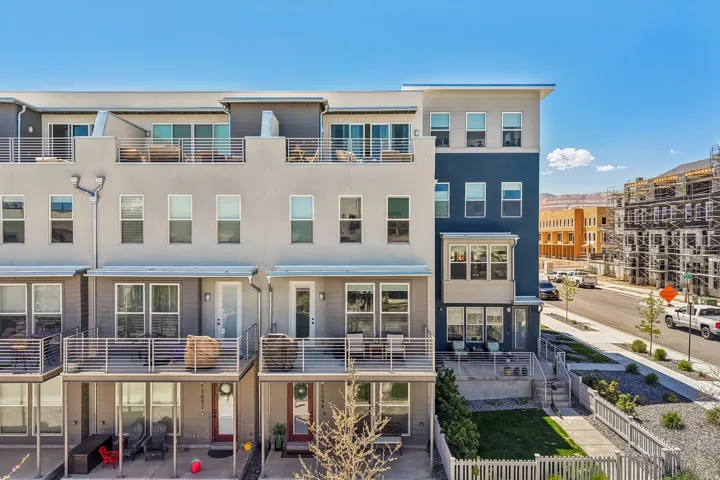 Modern multi-story townhome featuring a neutral exterior with a contrasting blue accent section