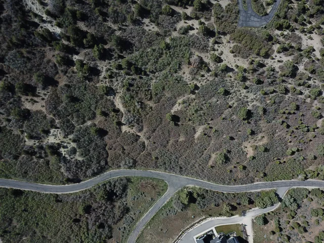Expansive undeveloped land featuring natural desert vegetation, varied topography, and an asphalt road
