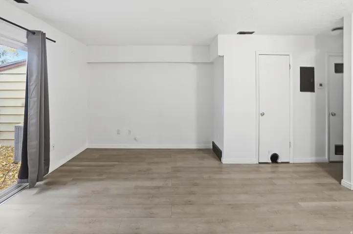 Spacious room featuring light wood-finish flooring, white walls, and a sliding glass patio door