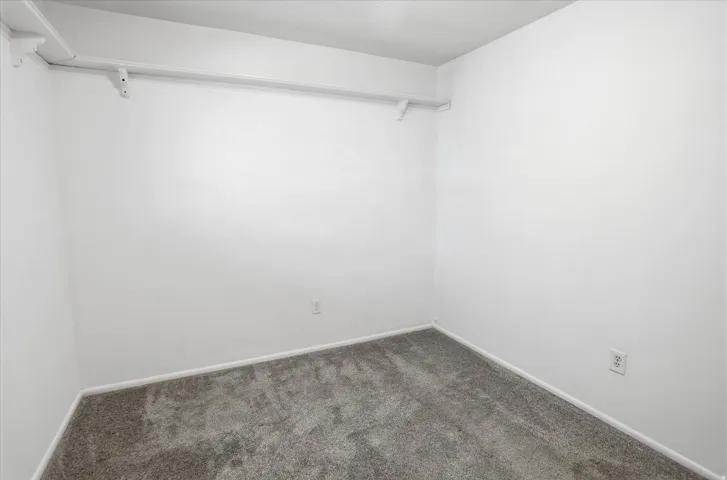 Interior room featuring light gray carpeting, white baseboards, and white painted walls