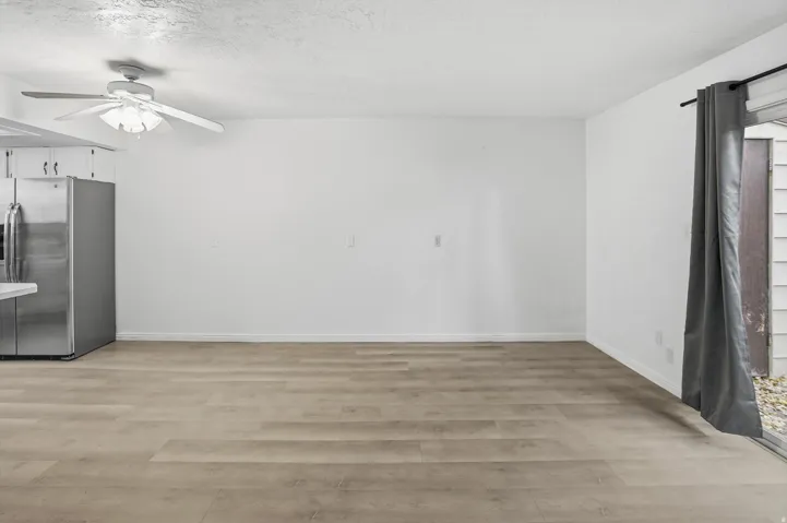 Open-concept living space featuring wood-finish flooring, white walls, and a ceiling fan