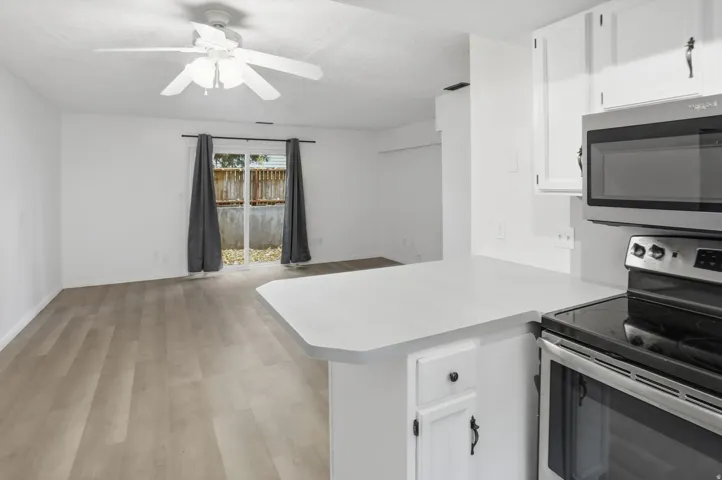 Open-concept living space featuring wood-finish flooring, a ceiling fan, and sliding glass doors