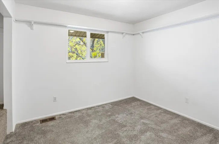 Room featuring neutral wall paint, gray carpet, a double-paned window, and a wall-mounted track system