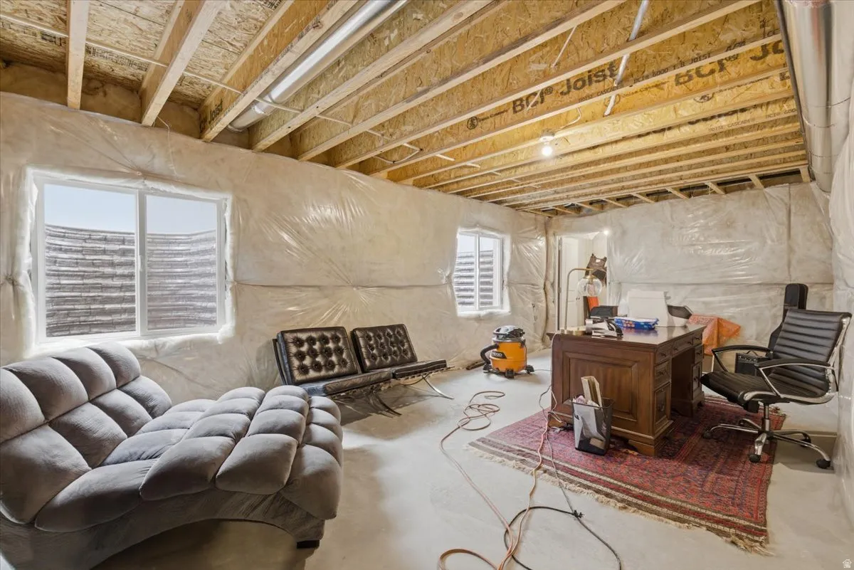 Unfinished basement space featuring exposed wood joists and framed walls, concrete flooring, and two egress windows