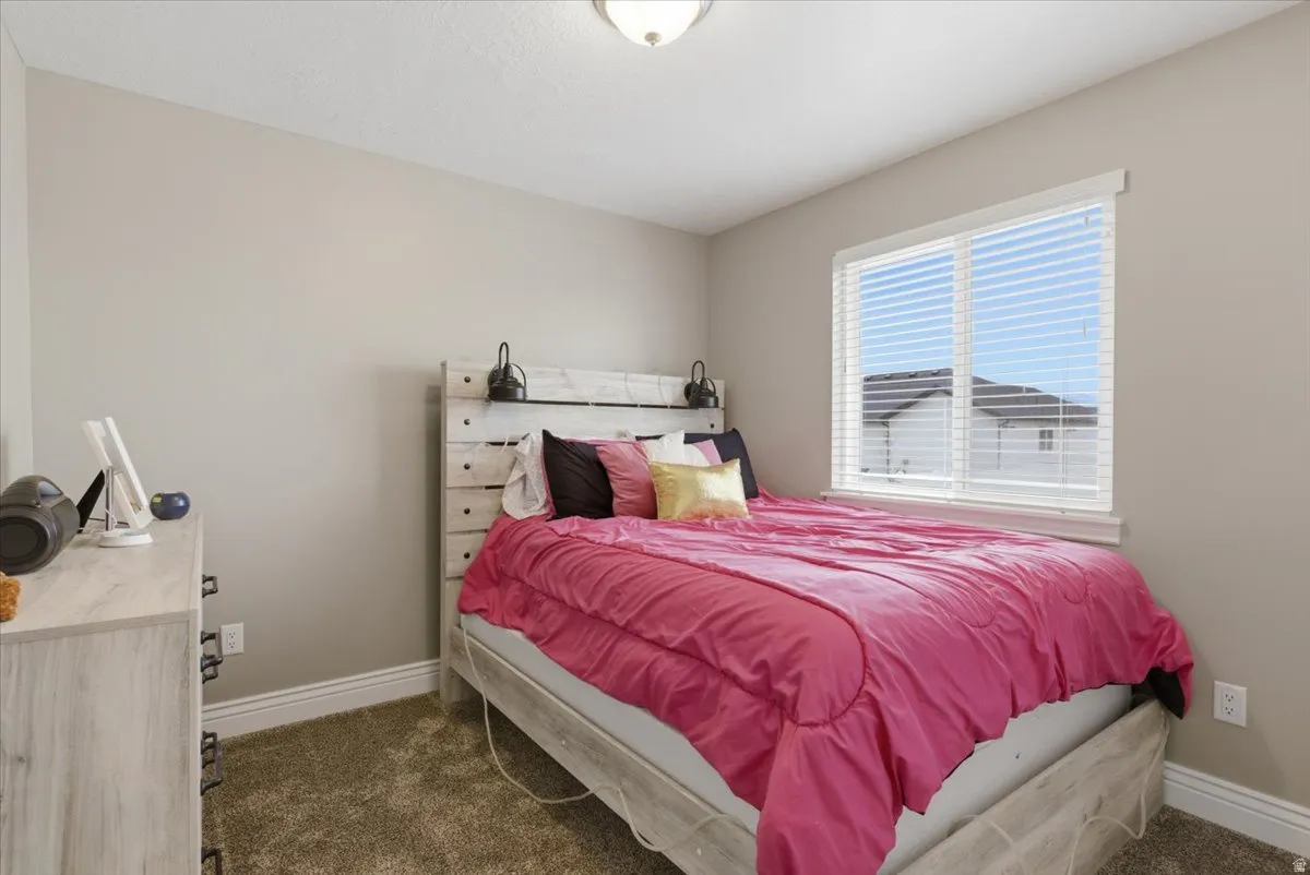 Bedroom featuring neutral wall paint, carpet flooring, a window with horizontal blinds, and a flush mount ceiling light