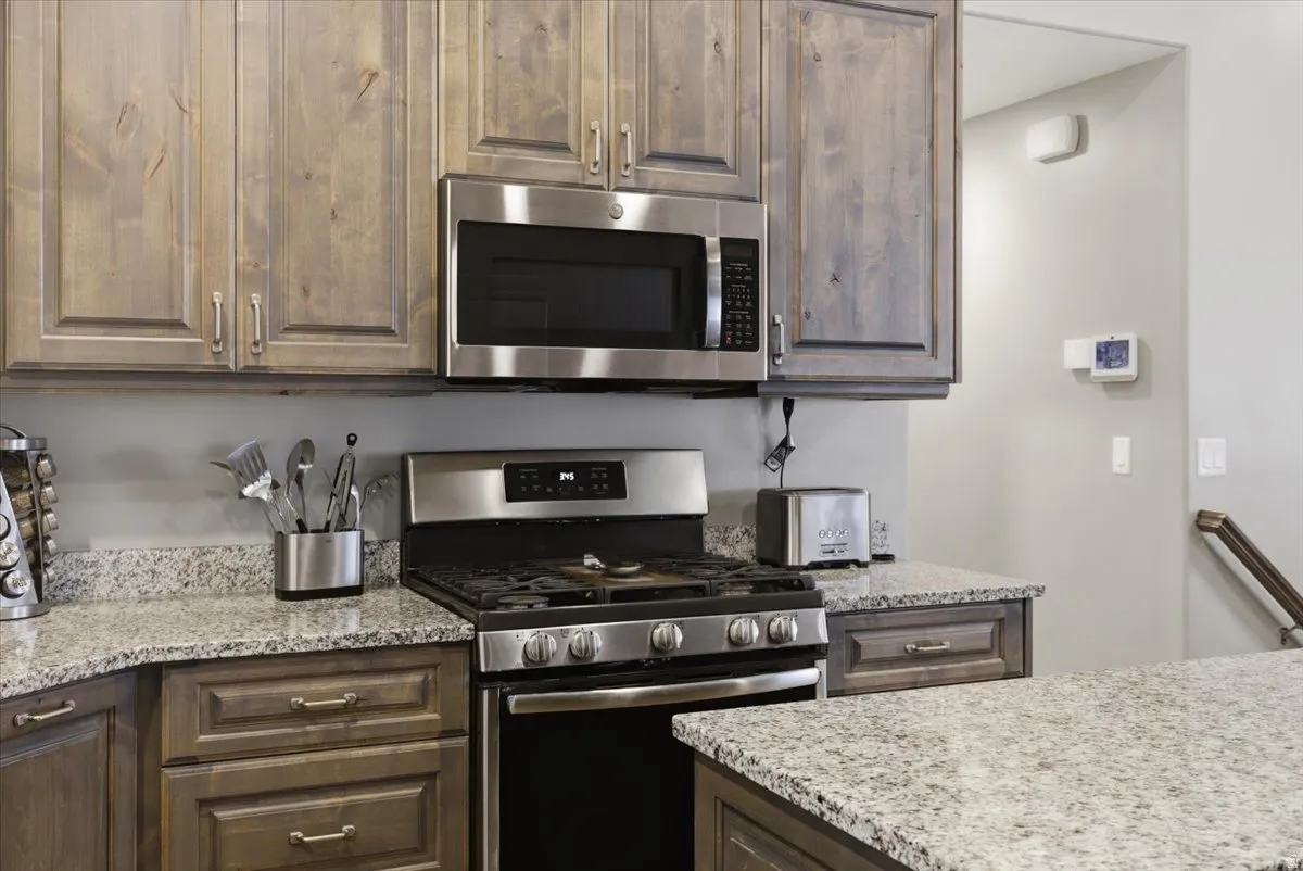 Kitchen featuring stainless steel appliances, wood-finish cabinetry, granite countertops, and a built-in microwave