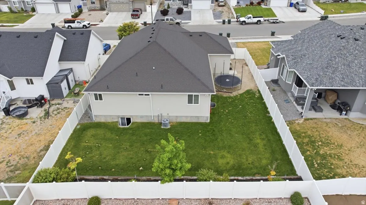 Expansive backyard featuring a manicured lawn, a young tree, and a vinyl privacy fence