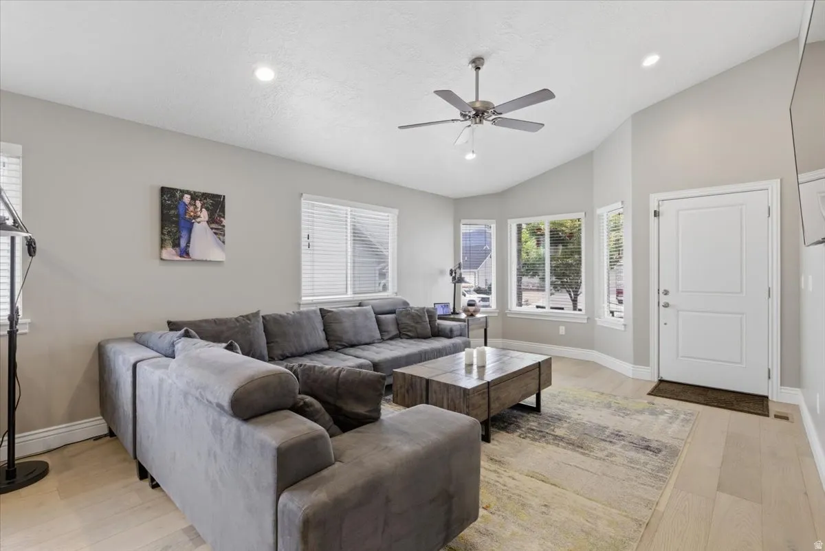 Living area with vaulted ceilings, recessed lighting, and wood-finish flooring