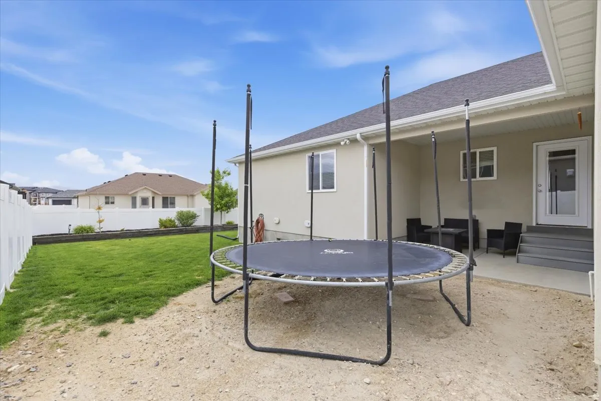 Rear exterior featuring a covered patio with direct access to the interior, a privacy fence, and a grassed yard space