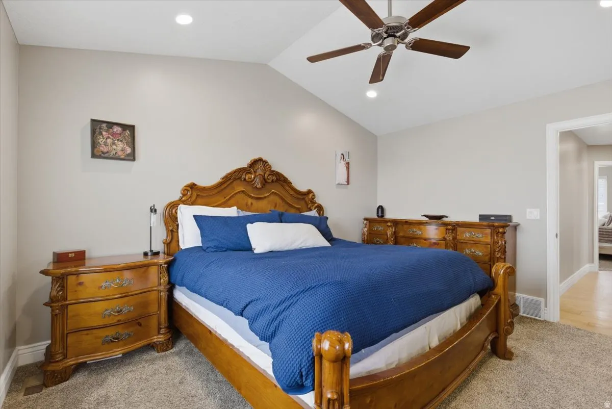 Vaulted ceiling with recessed lighting and a ceiling fan, carpet flooring, and neutral wall paint