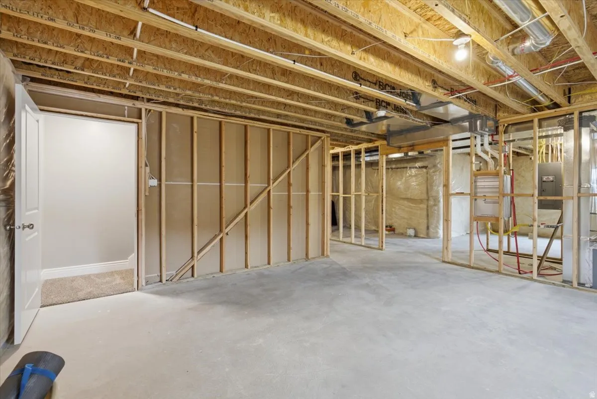 Unfinished lower level featuring exposed wood joists and concrete flooring